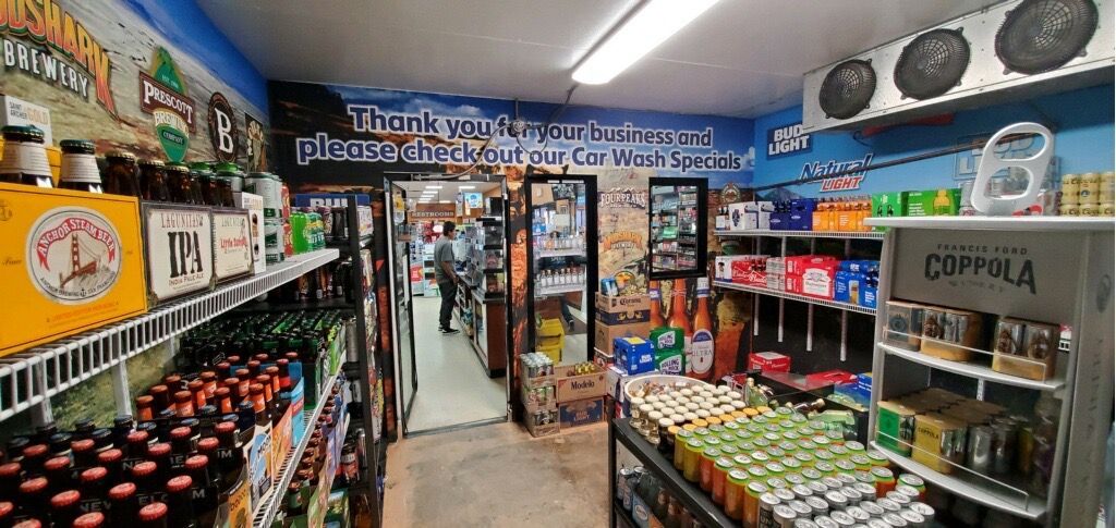 Inside a liquor store, shelves of beverages line the walls, a person walks through the aisle.