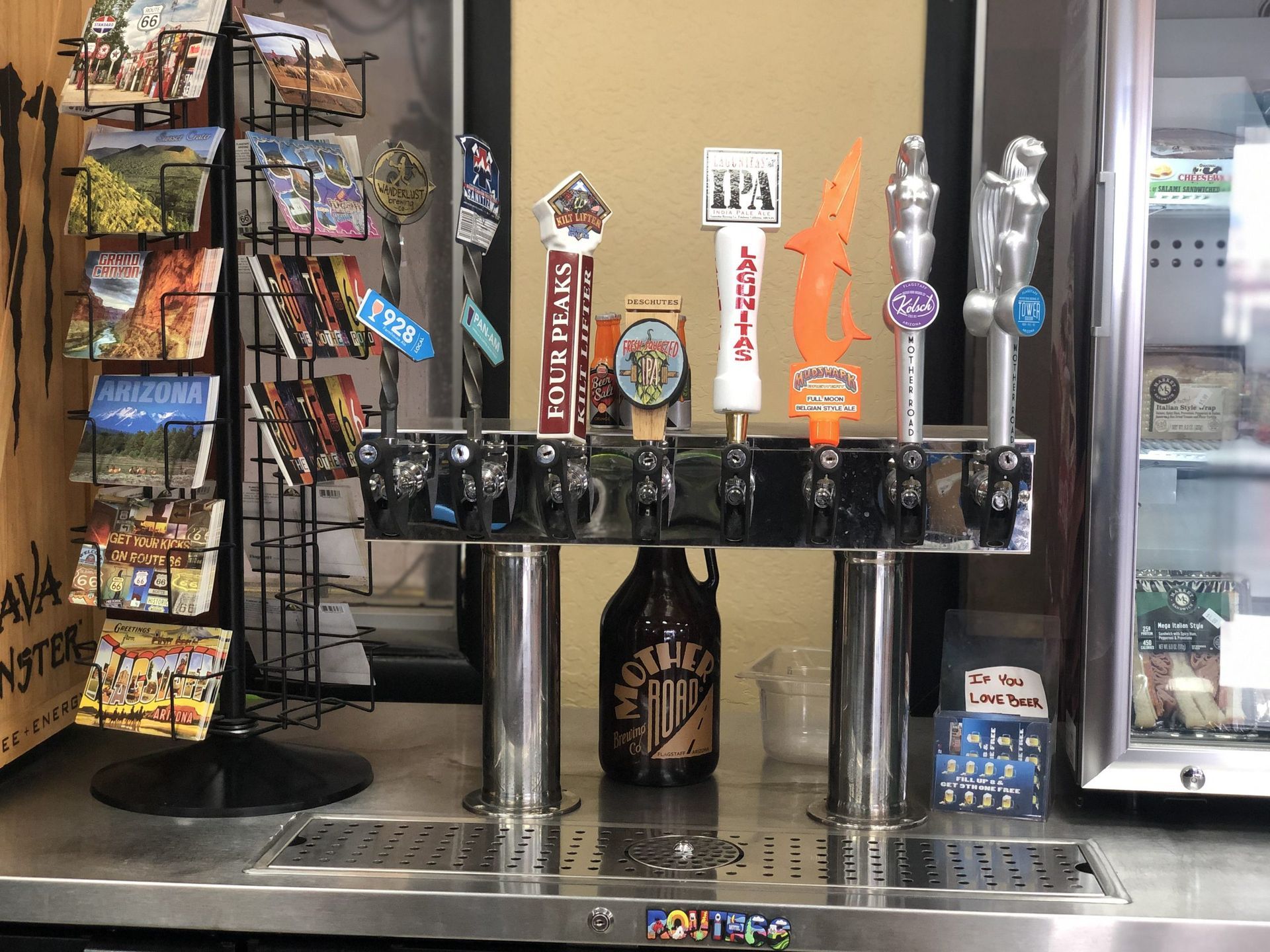 Bar with beer taps, postcards, and growler, in a restaurant setting.