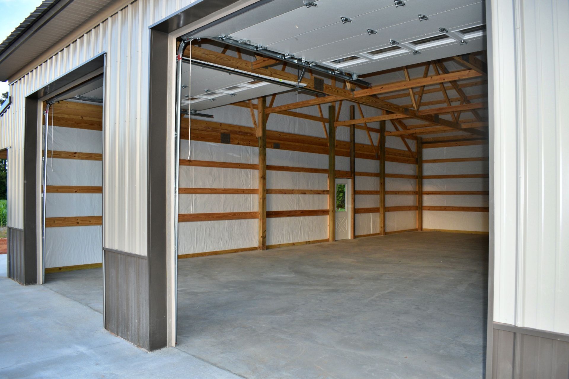 Open metal storage building with a large empty garage bay and concrete floor