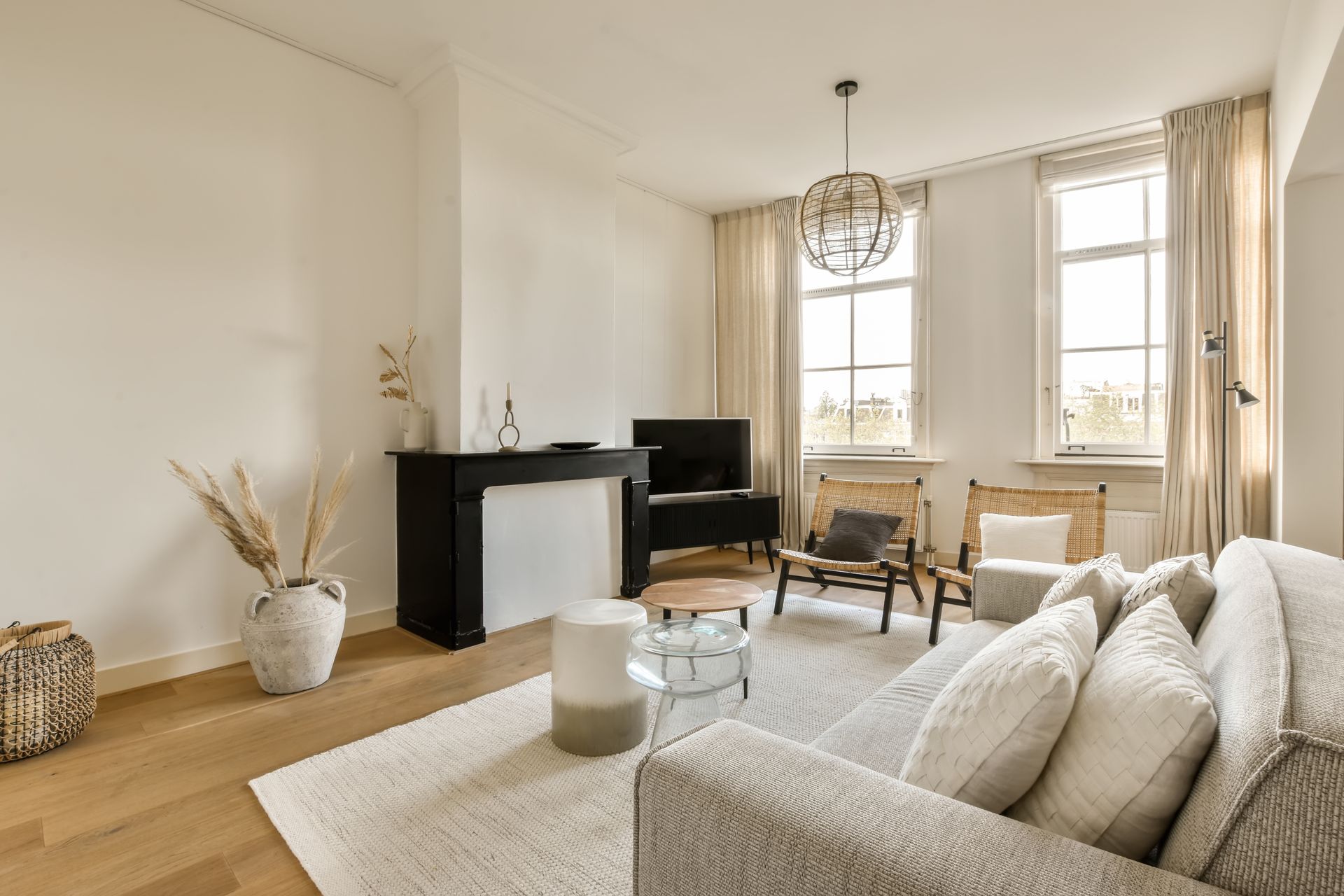 Bright living room with beige sofa, TV, fireplace, and large windows letting in natural light
