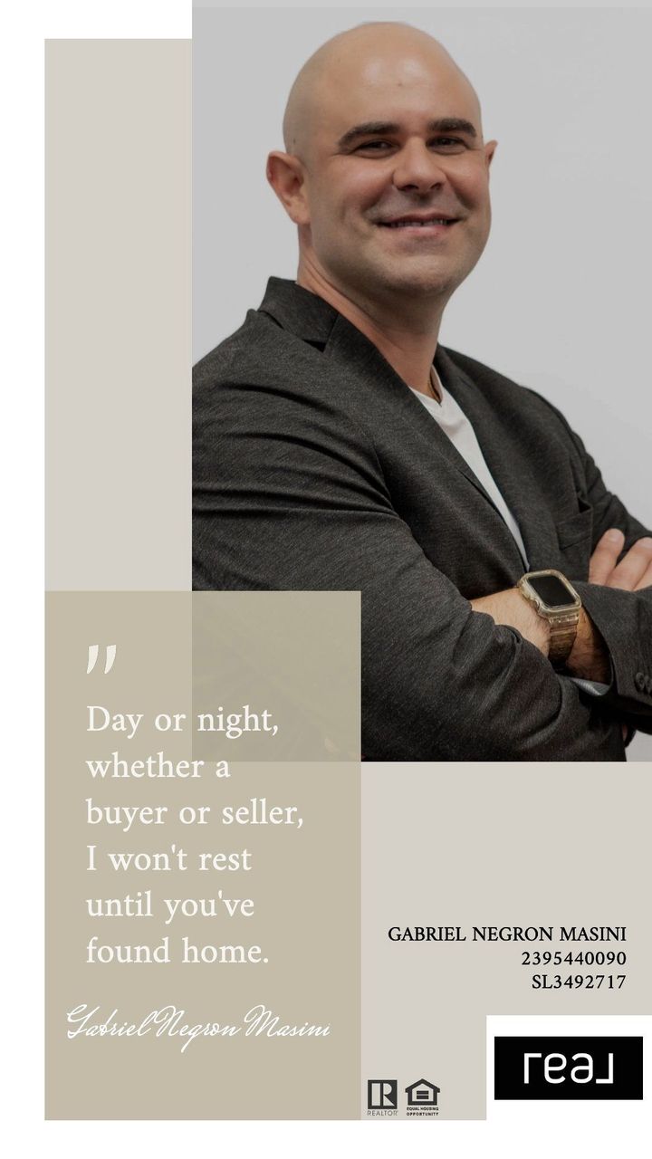 A bald man in a suit is standing with his arms crossed