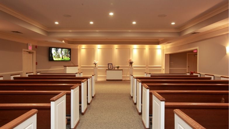 A church with rows of benches and a television on the wall.