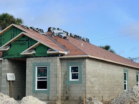Partially built cinder block house with red roof and open windows under construction.
