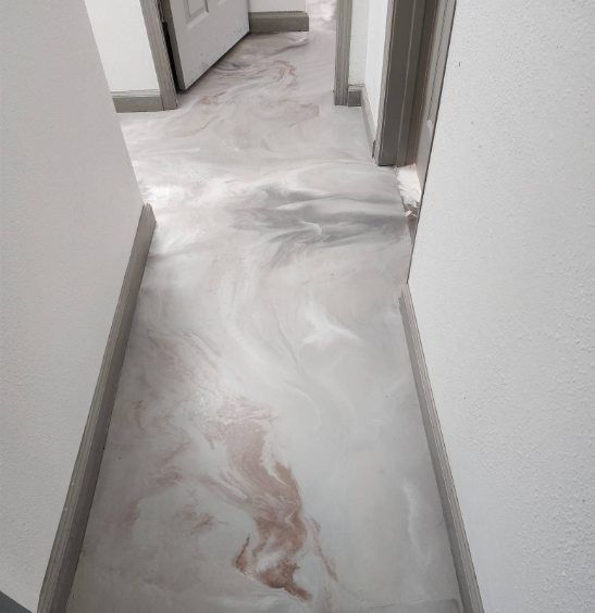 A hallway with a marble floor and white walls.
