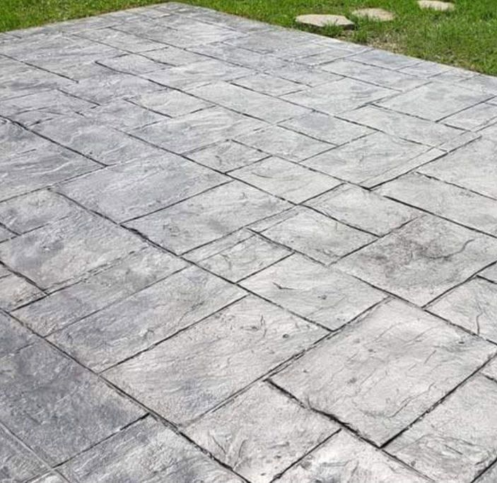 A close up of a concrete patio with a grassy area in the background.