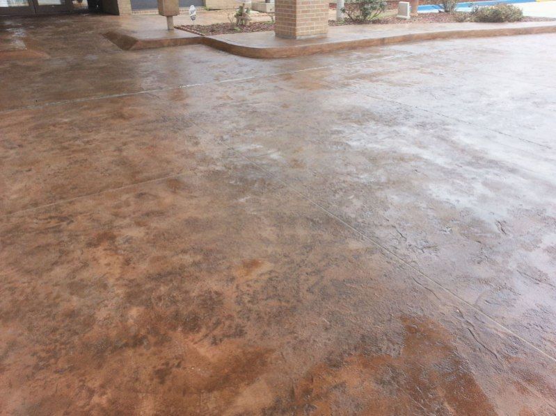A concrete driveway with a pool in the background