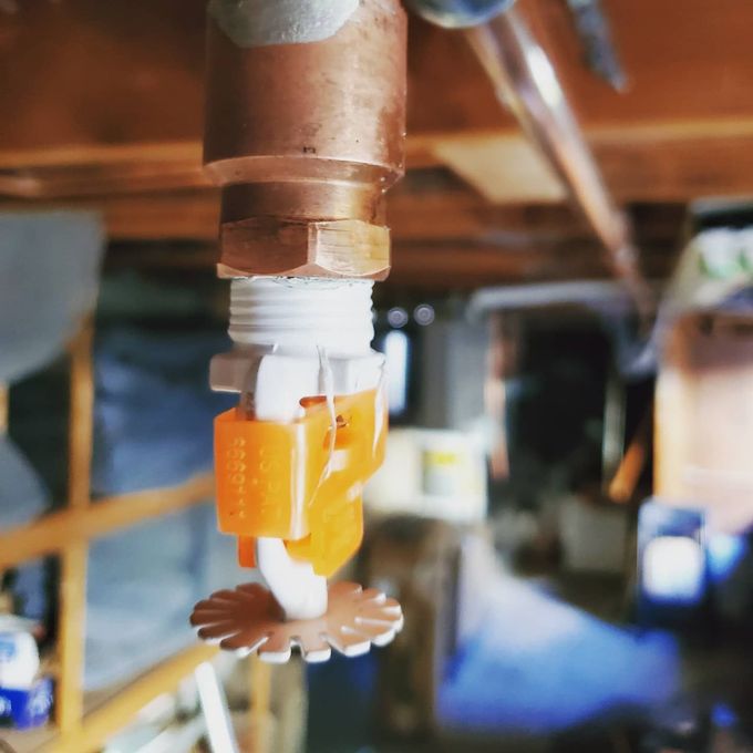 A copper pipe with an orange sprinkler attached to it