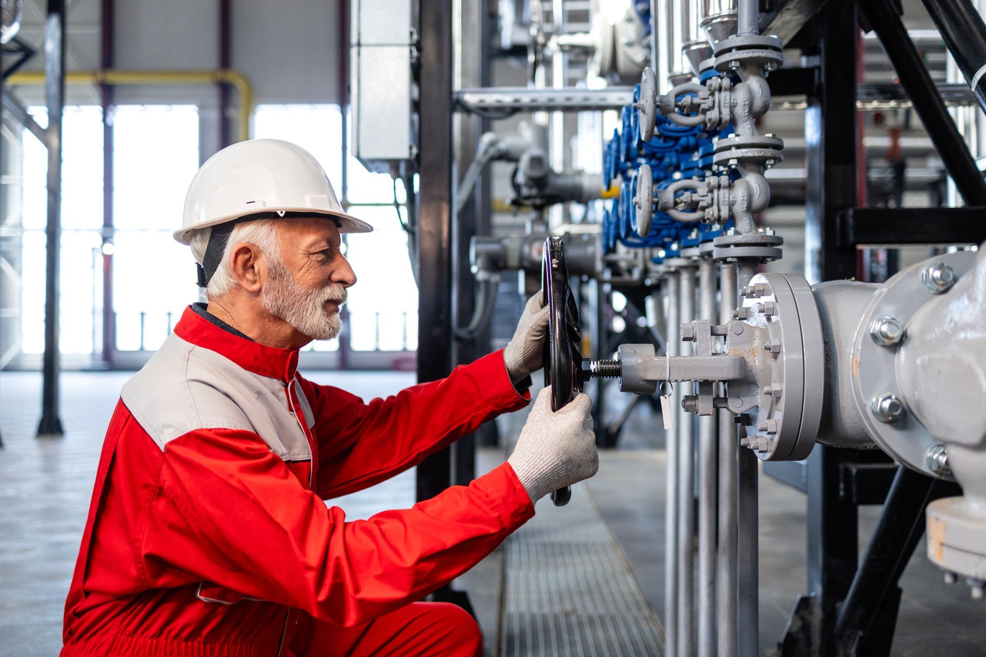 Engineer adjusting valve on piping, showcasing industrial boiler operation at a manufacturing plant. Engineer adjusting valve on piping, showcasing industrial boiler operation at a manufacturing plant.