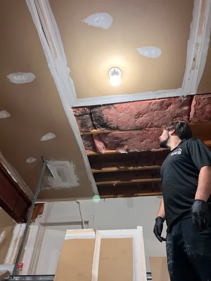 a man is standing in a room looking up at the ceiling .