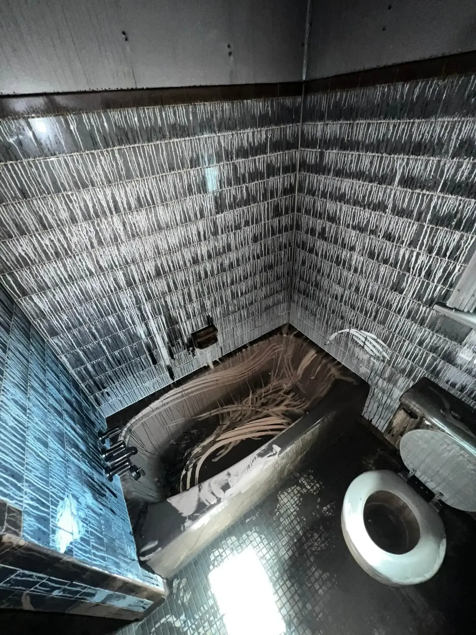 a bathroom with fire damage to 
 a bathtub , toilet , and shower .