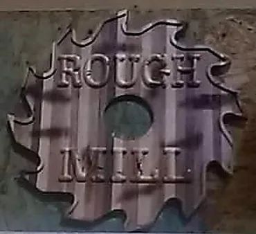 A metallic saw blade shaped sign against a corrugated wall, embossed with the text