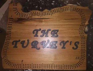 A wooden cribbage board shaped like the state of Oregon, engraved with the words