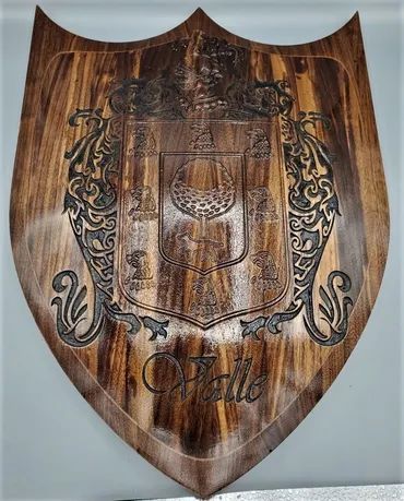 A wooden shield featuring an engraved coat of arms and the name