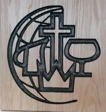 A black wood-burned design featuring a cross, a crown, and a chalice, layered over a stylized globe, on a wood background.