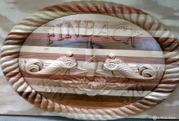 A horizontal oval wooden plaque with a carved rope border, featuring the name
