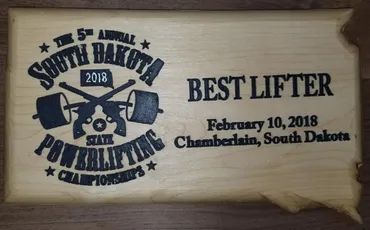 A wooden plaque shaped like South Dakota, inscribed