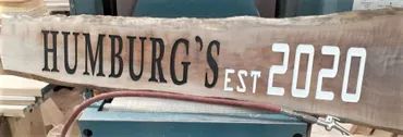 A rustic wooden sign with live edges reads