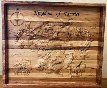 A wooden carving of the Tamriel map featuring regional names, a compass rose, and a deep frame.