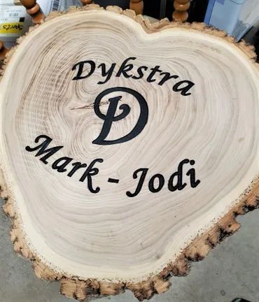 A circular wooden tree slice with live edges, engraved with