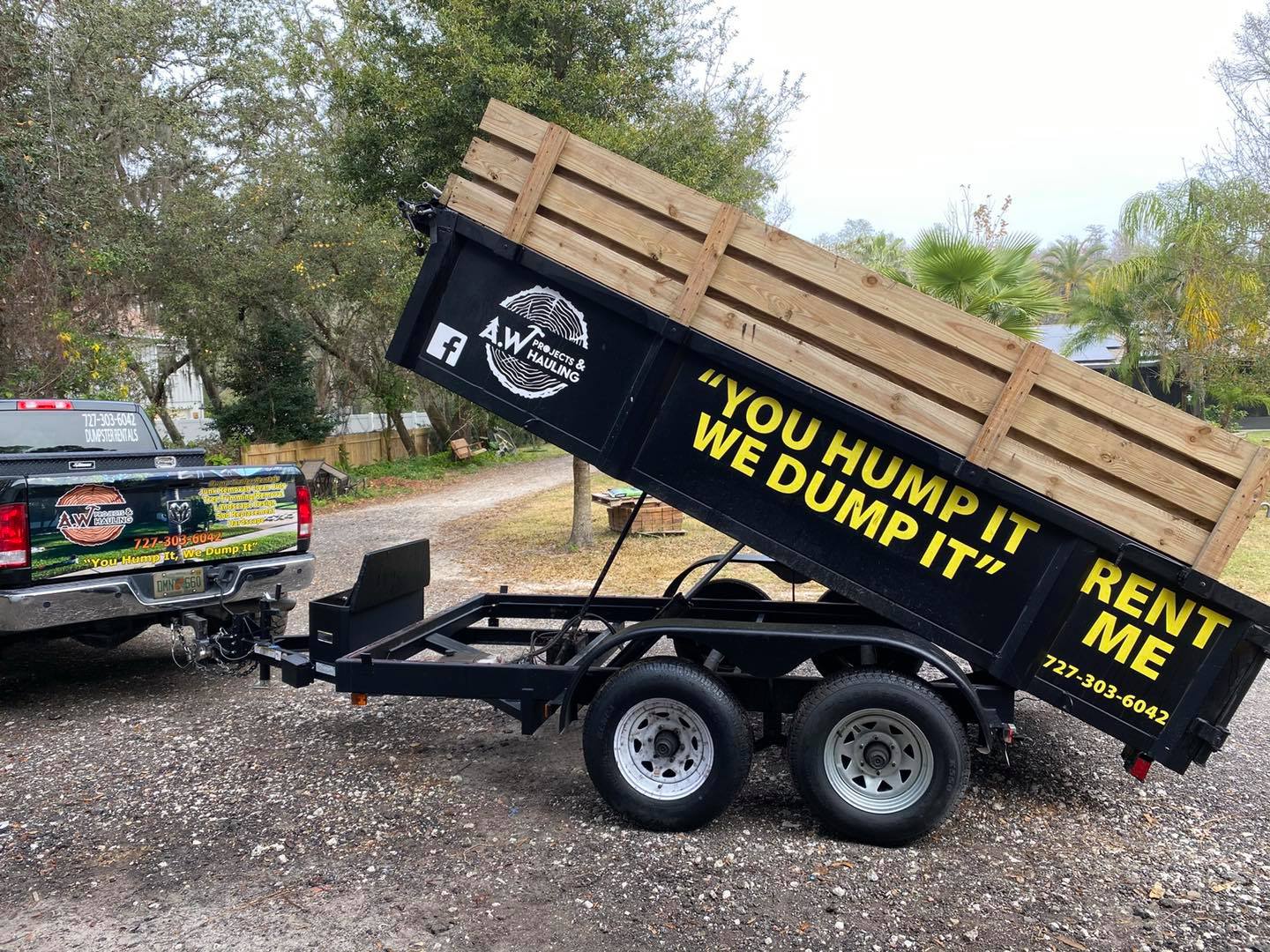 A dumpster trailer is parked next to a truck.