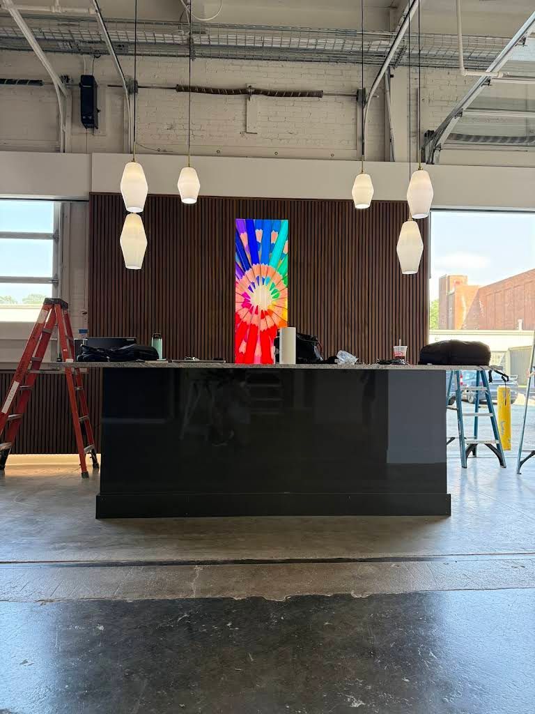 A black bar with a colorful vertical display, brown curtain backdrop, and hanging lights in a garage setting.