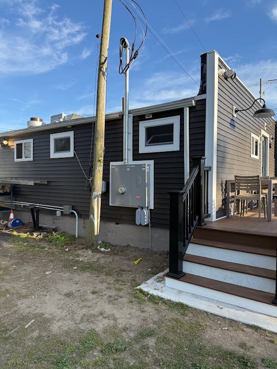 Dark gray building with electrical box, utility pole, and outdoor deck.
