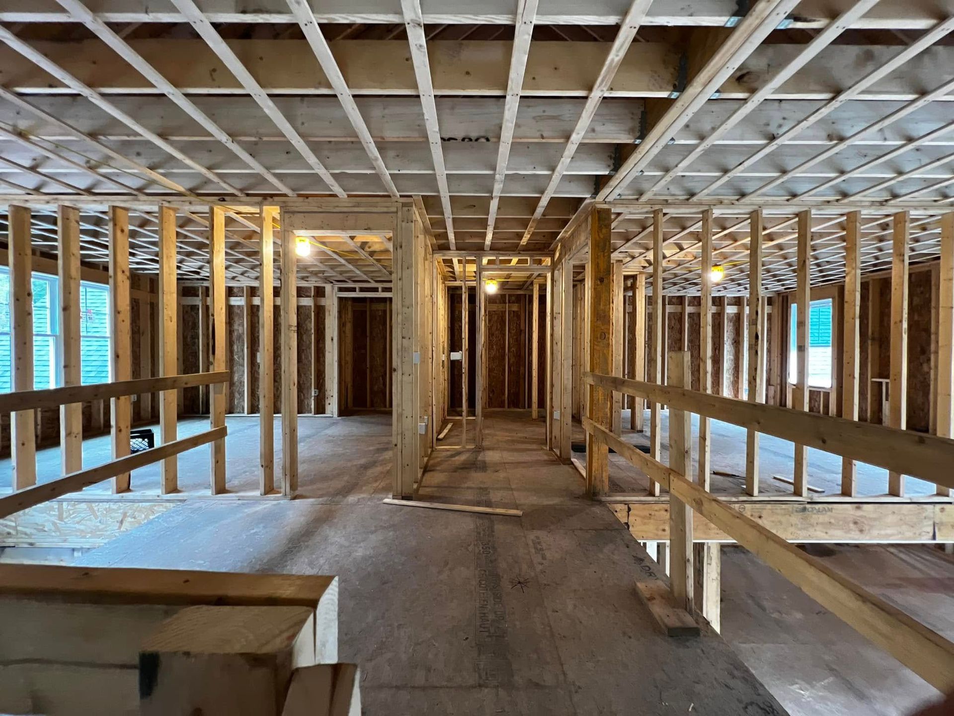 Interior framing of a building under construction, showing wooden studs, beams, and floorboards.