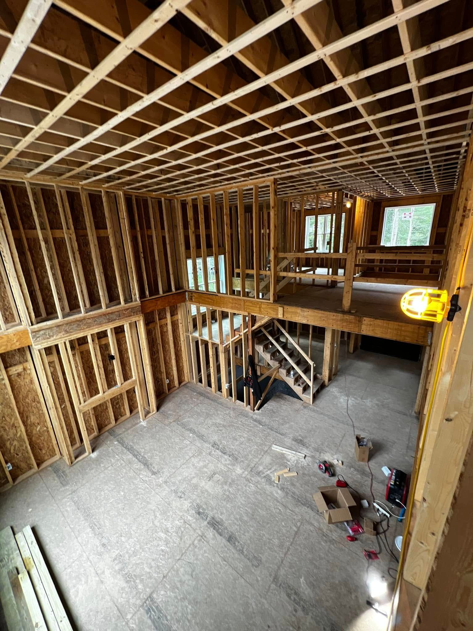 Interior wood framing of a house under construction, with a second-floor level and open staircase.
