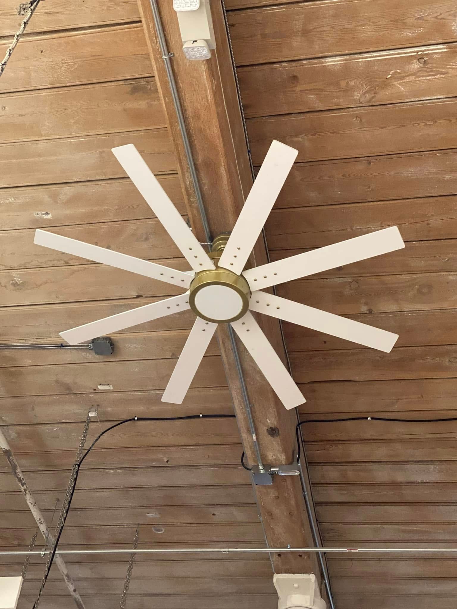 Ceiling fan with white blades and brass accents on a wood-beam ceiling.