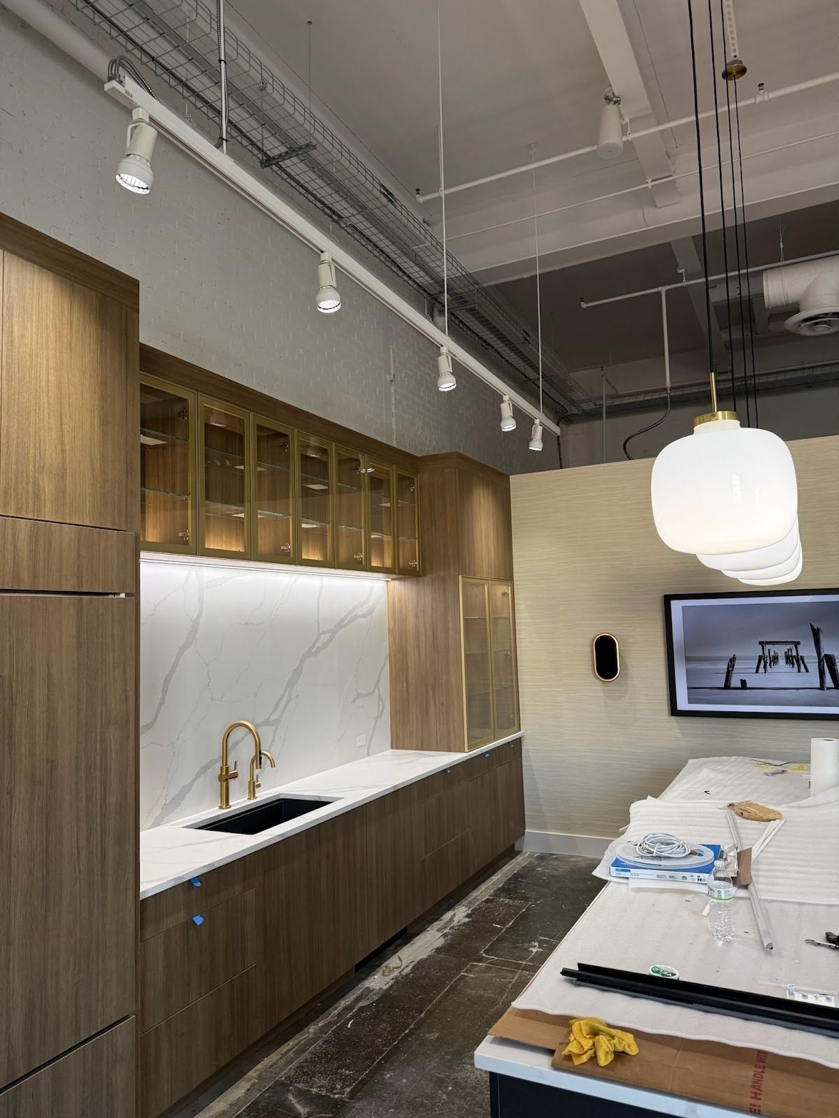 Modern kitchen with wood cabinets, marble backsplash, and gold faucet. Track lighting and pendant light.