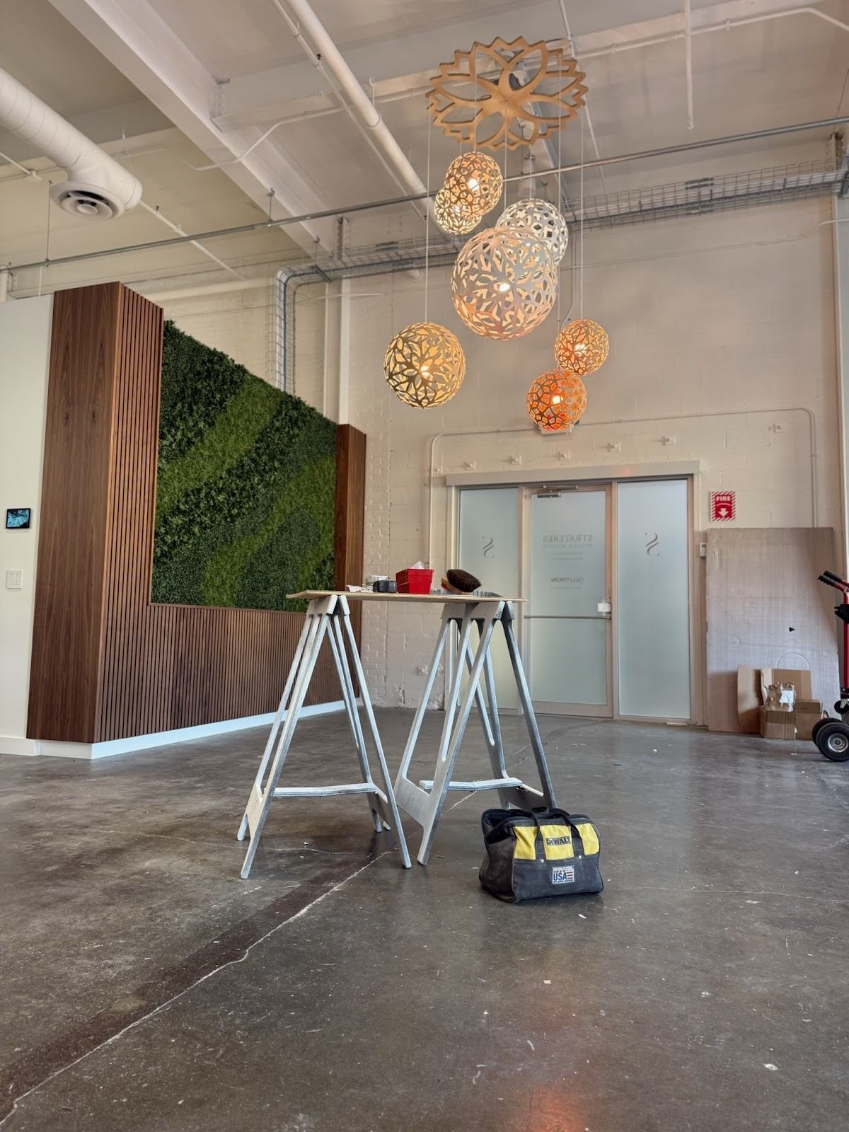 Interior with a faux-green wall and wooden accent. Hanging pendant lights over a doorway, tools, and a ladder are present.