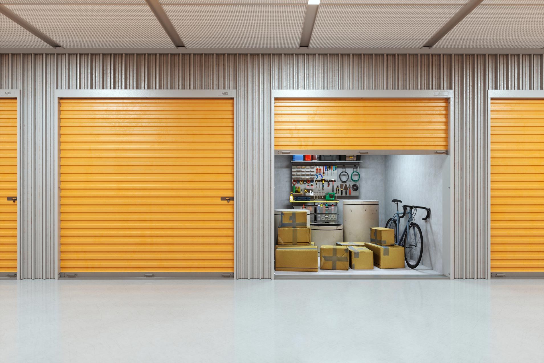 A bright, clean storage unit with a yellow garage door partially open, revealing boxes, a bicycle, a