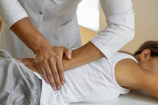 A woman laying on bed getting back adjusted from a chiropractor.
