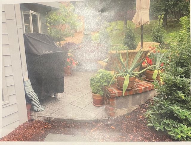 A picture of a patio with potted plants and an umbrella