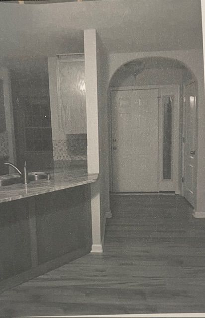 A black and white photo of a kitchen with a sink and a door.