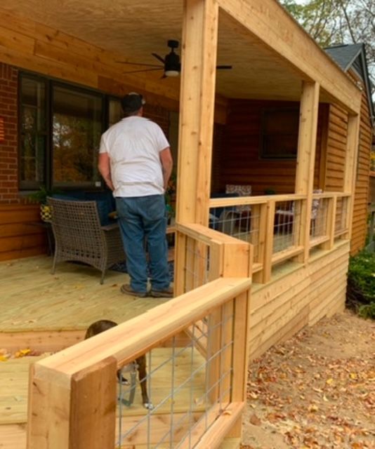 A man standing on a porch with a dog