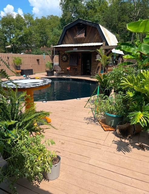 A deck with a swimming pool and a barn in the background