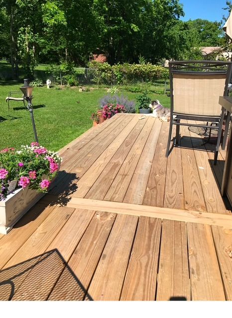 A wooden deck with chairs and flowers on it