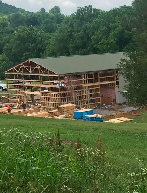 A large building is being built in the middle of a grassy field.