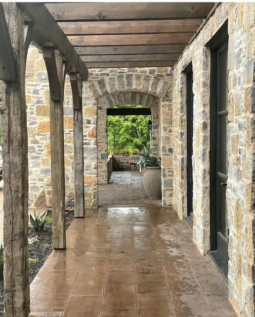 A stone walkway with a wooden pergola over it
