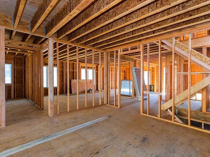 The inside of a house under construction with wooden beams and stairs.