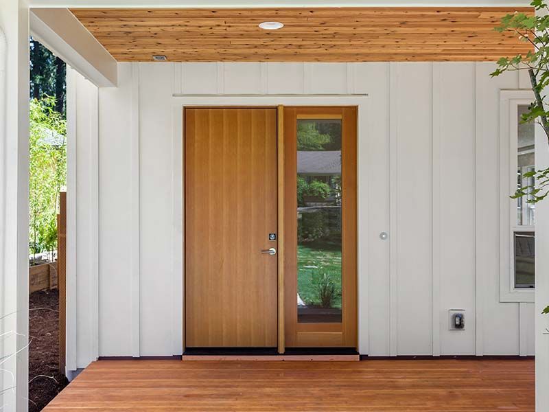 A white house with a wooden door and a wooden deck