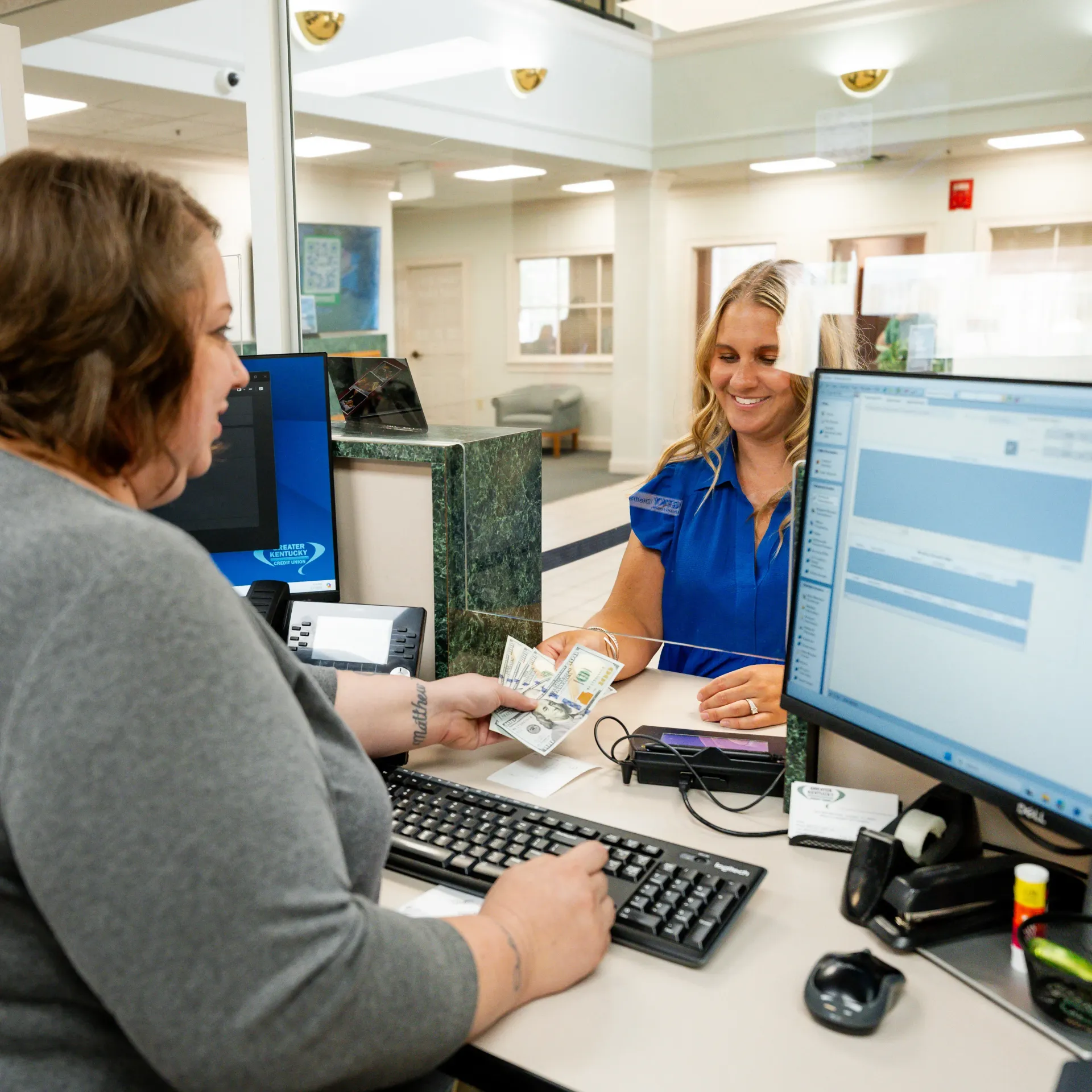 Bank teller hands money to a customer at a bank counter.