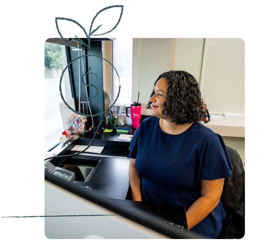 Woman in blue shirt seated at desk, looking to the side. Office setting.