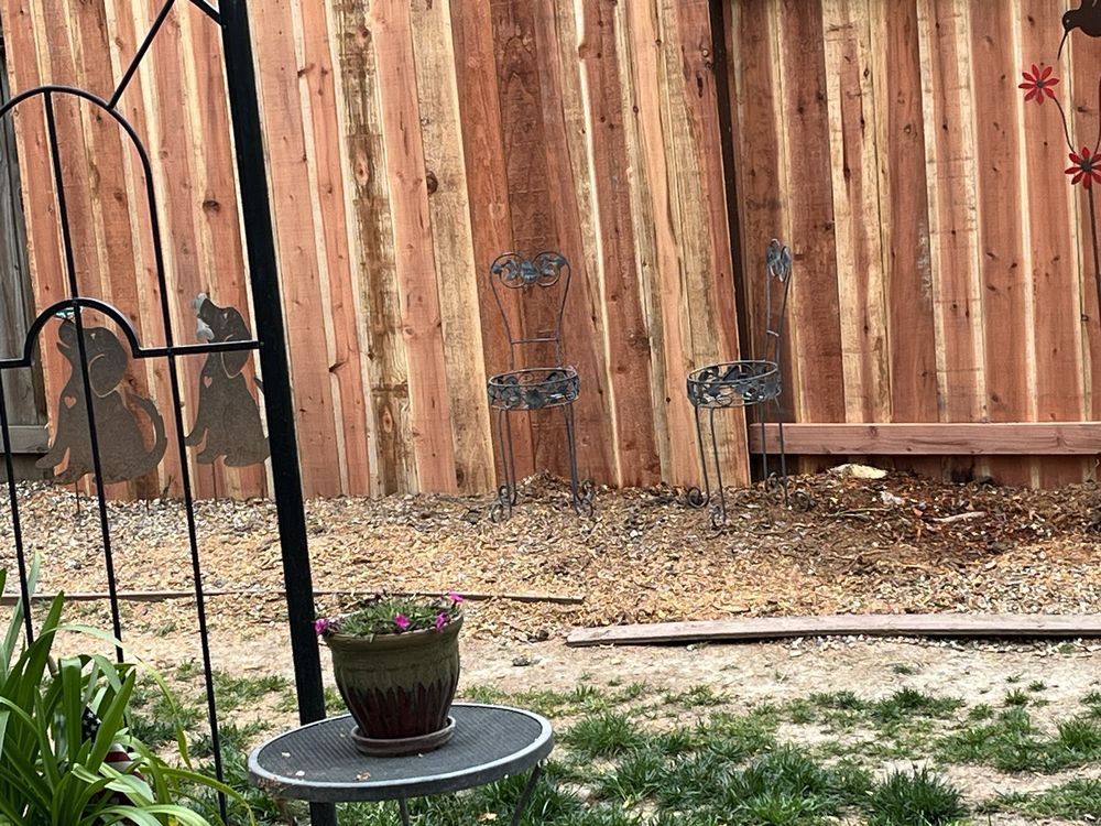 A potted plant is sitting on a table in front of a wooden fence.