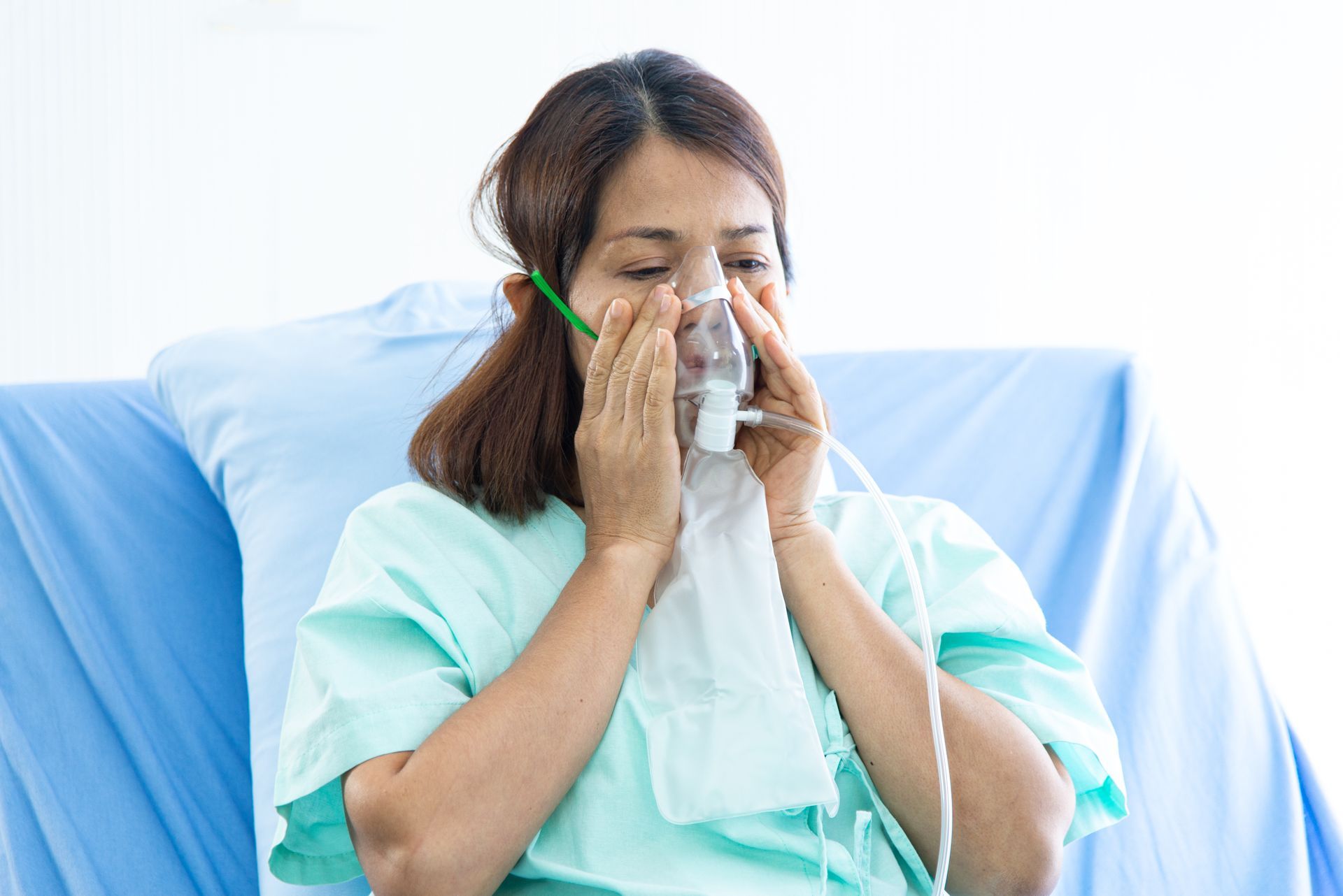 A woman is laying in a hospital bed with an oxygen mask on her face.