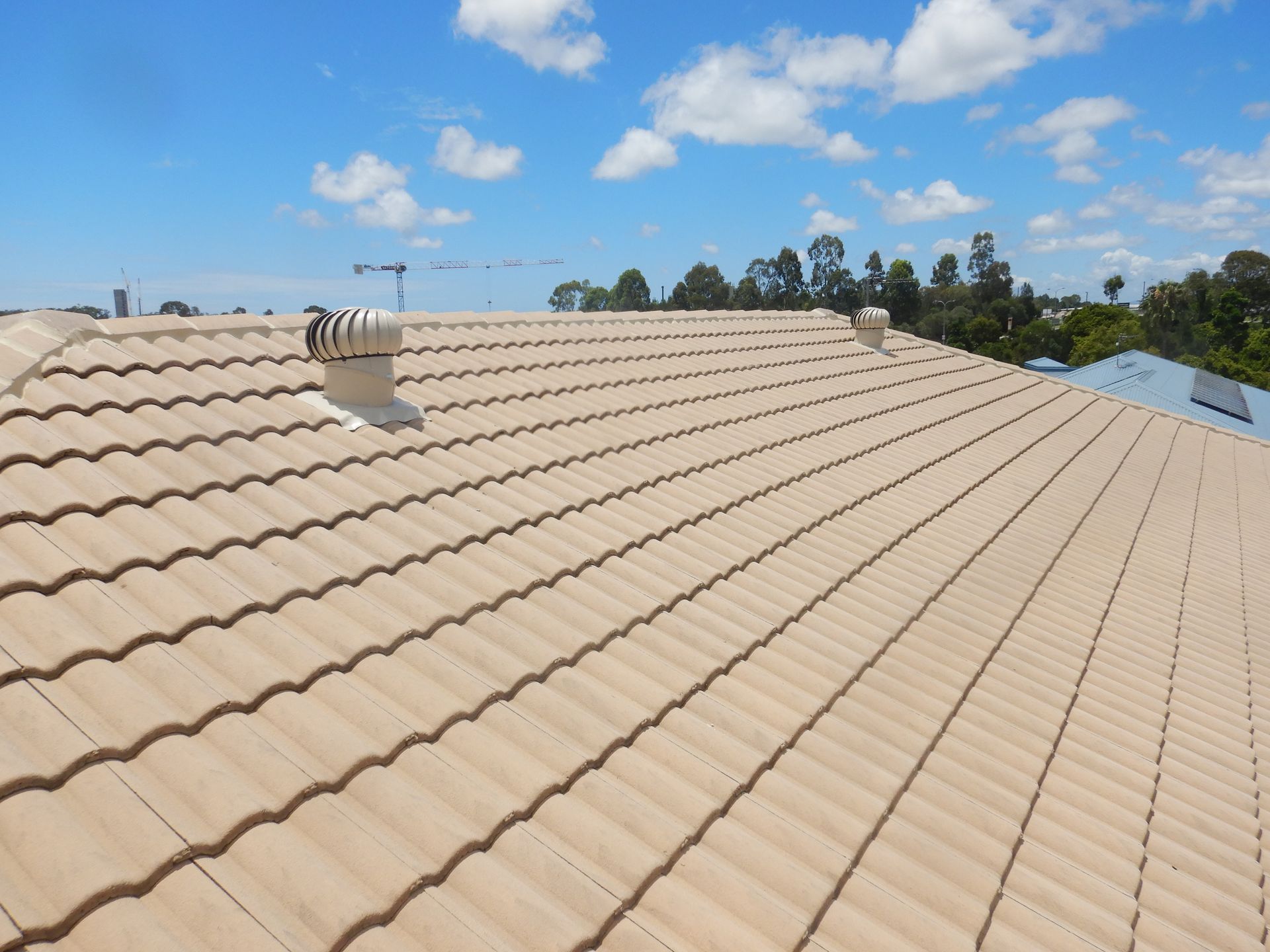 A Man Is Cleaning A Roof With A High Pressure Washer — Gold Coast Roof Repairs in Benowa, QLD