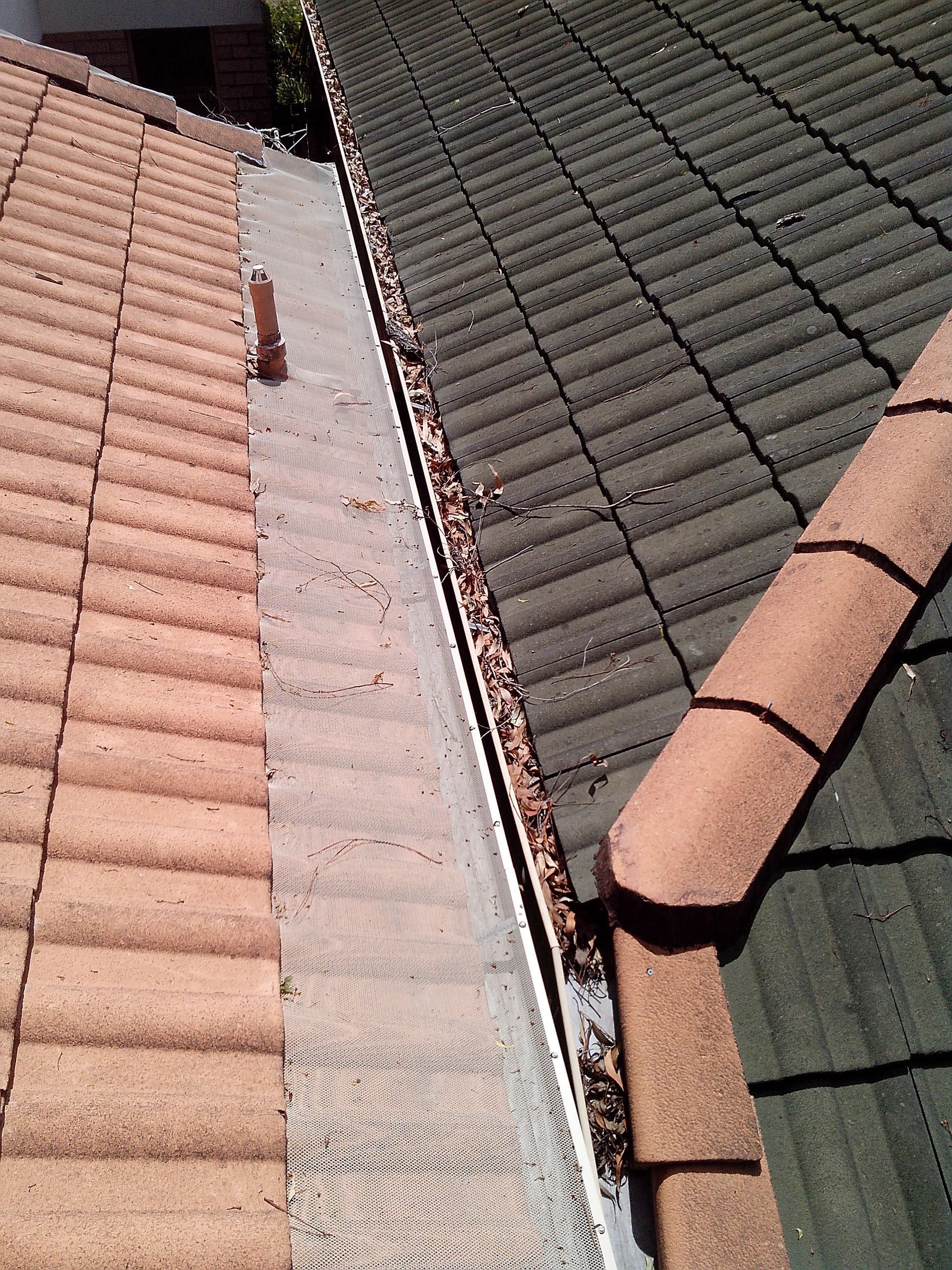 A Yellow Leaf Is Sitting On Top Of A Gutter On A Roof — Gold Coast Roof Repairs in Mudgeeraba, QLD