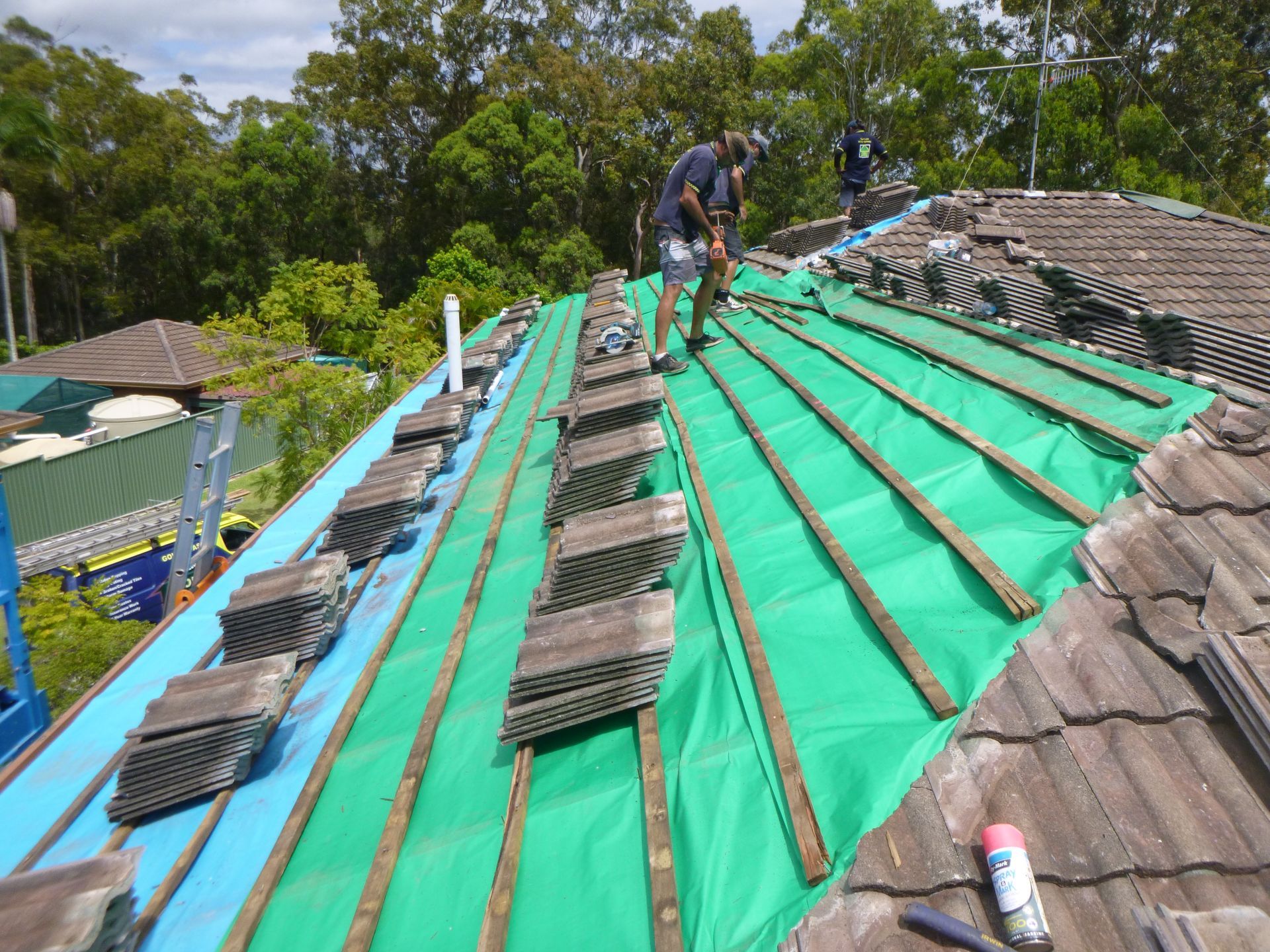 Two Men Are Working On The Roof Of A House — Gold Coast Roof Repairs in Mudgeeraba, QLD