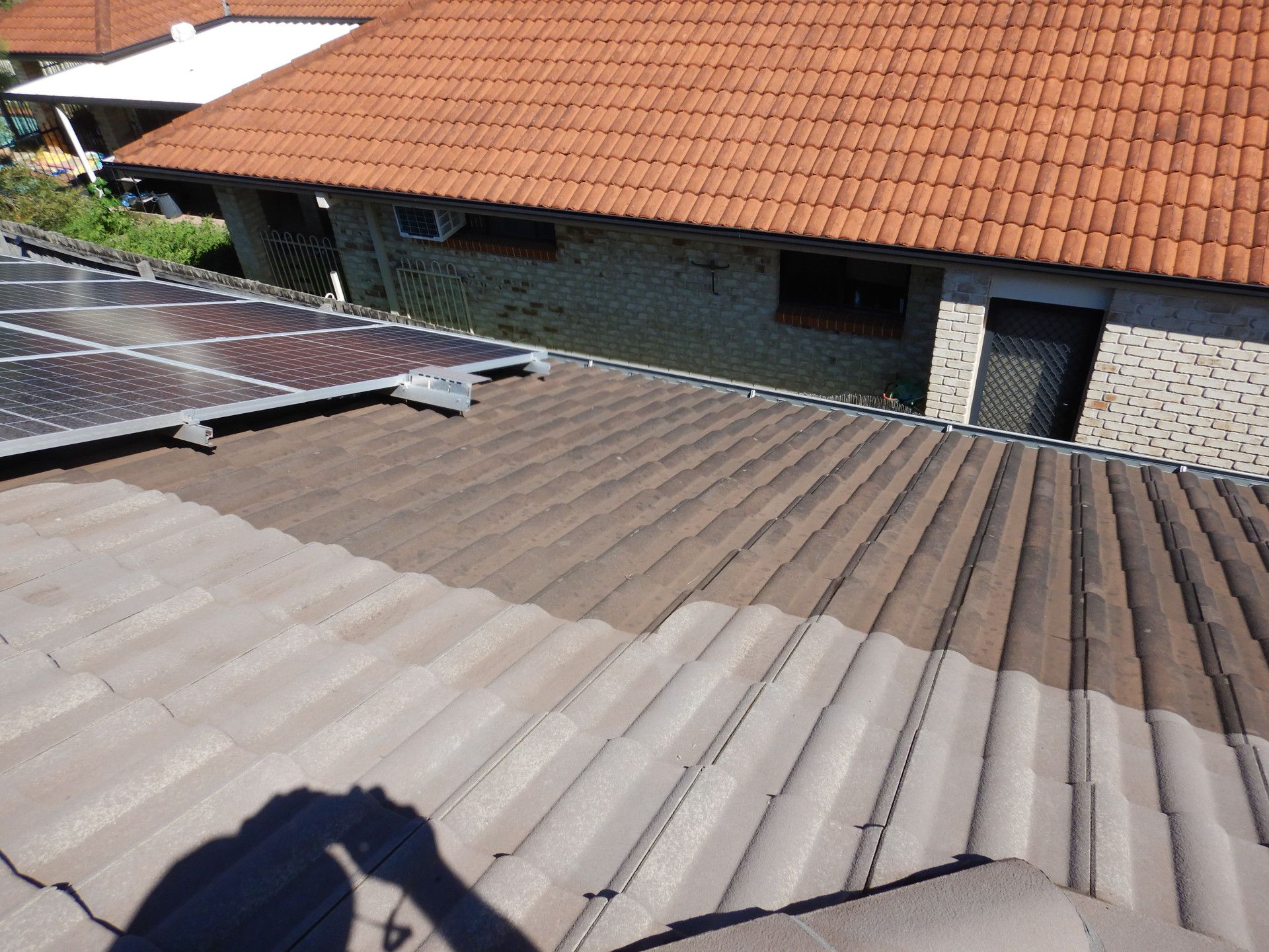 Robot Cleaning The Tiles on a Roof With A Solar Panel And A High Pressure Washer — Gold Coast Roof Repairs in Mudgeeraba, QLD